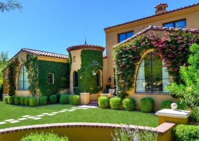 Luxury home back entry with manicured lawn, custom paver path, and maintained trees
