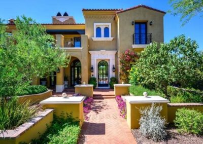 Newly planted trees and shrubs with layered landscaping leading to a custom-designed entryway and a long driveway featuring varied hardscape elements.