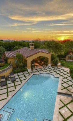 Custom Pavers and Outdoor Living Spaces Painted desert landscape featuring custom pavers surrounding a pool, outdoor grill, multiple covered seating areas, and well-maintained trees and shrubs.